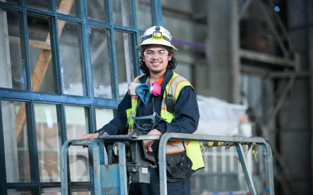 Man wearing hard hat and protective gear smiling at the camera