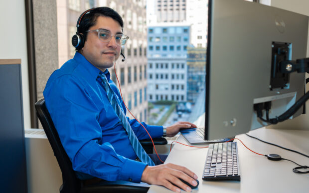 Man wearing a headset and sitting in front of a computer.