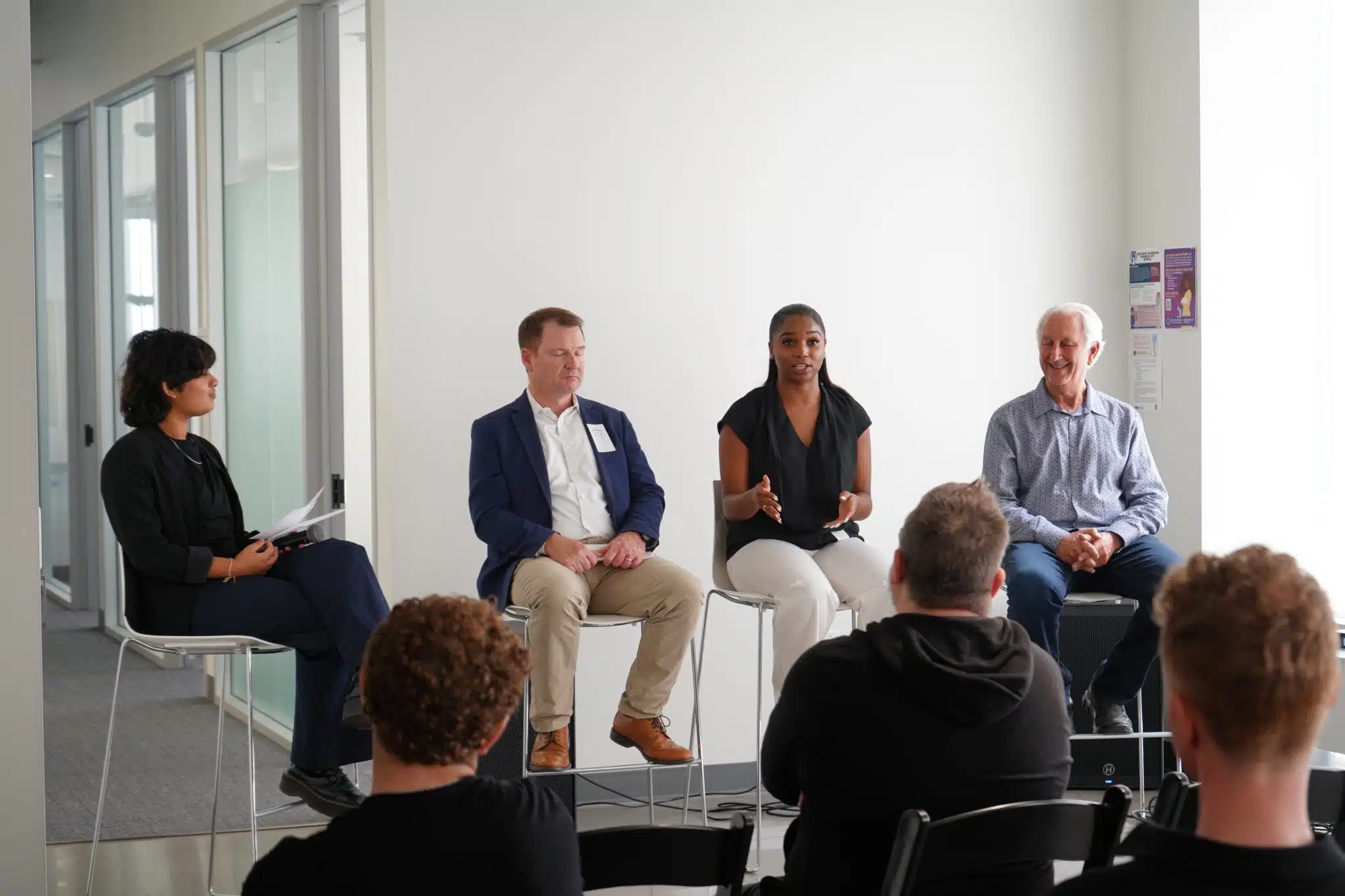 Four people sitting in front of a crowd during a panel discussion